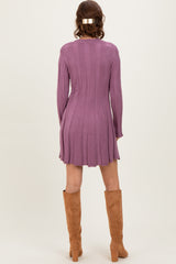 woman wearing a ribbed purple long sleeve sweater dress with a flared hem and tan knee-high boots
