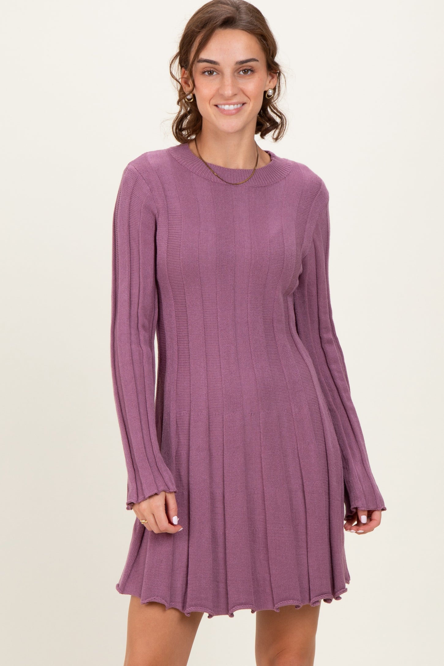 woman wearing a purple ribbed knit long sleeve dress with a flared skirt and scalloped hemline