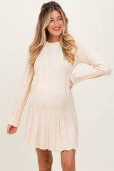 woman wearing a cream ribbed maternity sweater dress with long sleeves and a flowing skirt, showing her baby bump