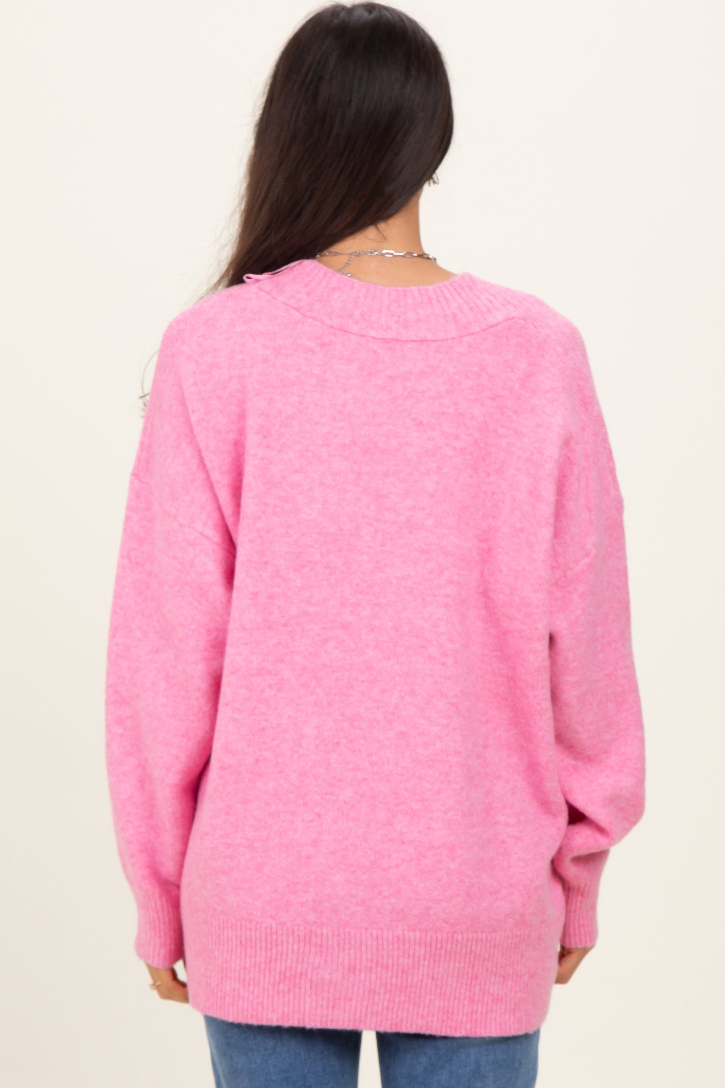 woman wearing a soft pink oversized sweater with a back knit design and long sleeves