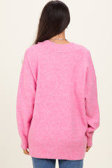 woman wearing a soft pink oversized sweater with a back knit design and long sleeves