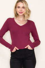 woman wearing a burgundy long sleeve v-neck top with fitted style and ribbed texture