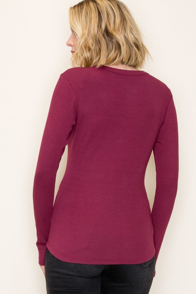 woman wearing a burgundy long sleeve fitted top, viewed from the back, styled with black jeans