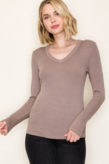woman wearing a taupe long sleeve v-neck top with a fitted style