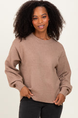 woman wearing a beige oversized sweater with balloon sleeves and a round neckline, styled with black jeans