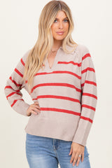 woman wearing a beige v-neck sweater with red stripes and slightly oversized fit, paired with blue jeans