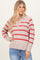 woman wearing a beige v-neck sweater with red stripes and slightly oversized fit, paired with blue jeans