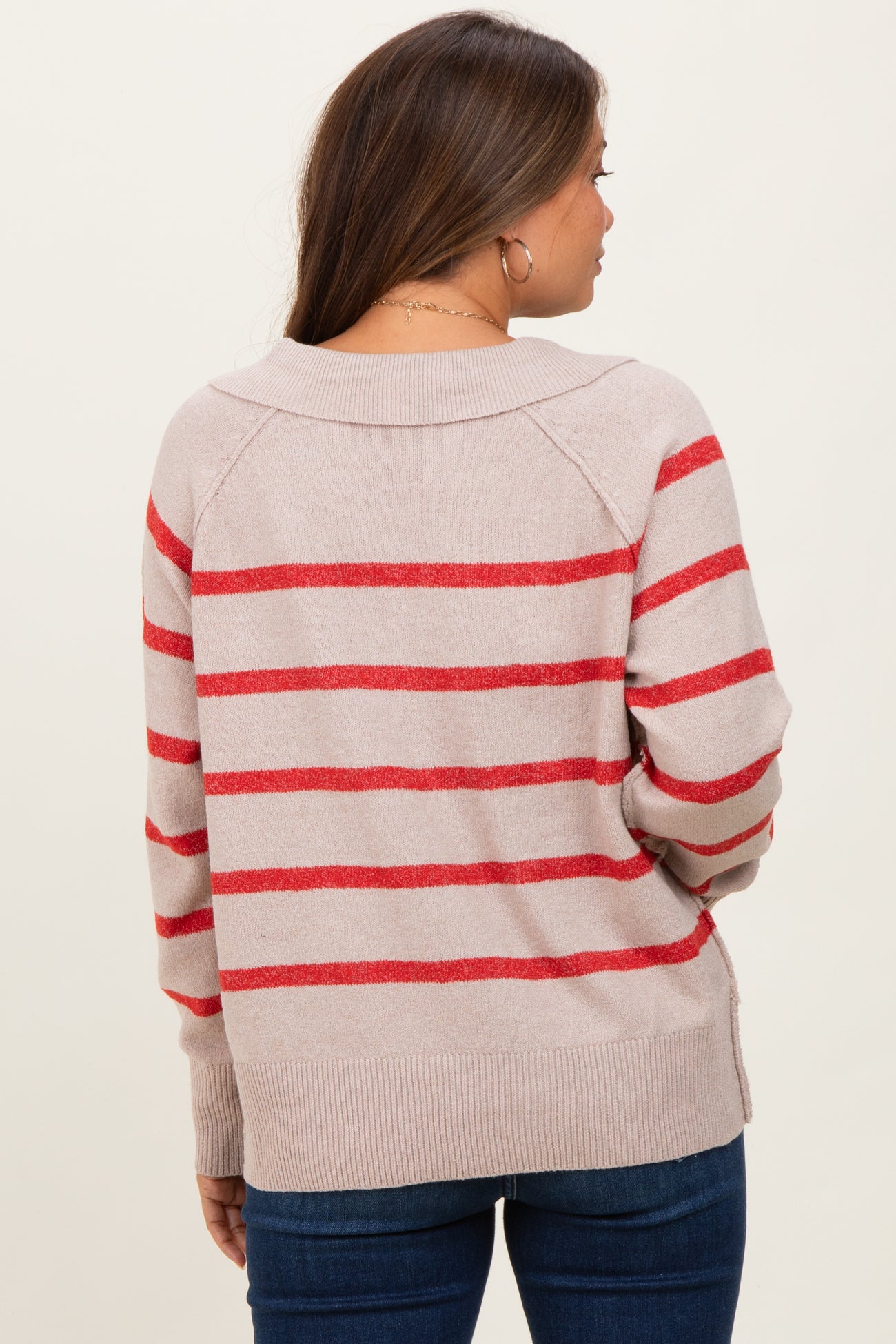 woman wearing a light beige maternity sweater with red stripes, viewed from the back