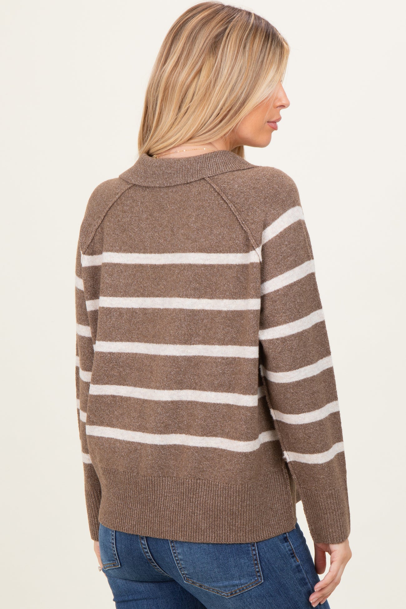 woman wearing a brown and white striped sweater with a relaxed fit and raglan sleeves, seen from the back