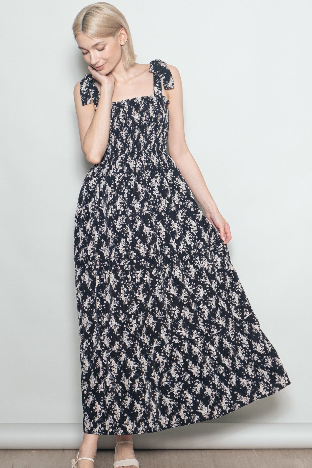 woman wearing a navy floral maxi dress with tie straps and a smocked bodice