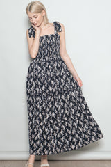woman wearing a navy floral maxi dress with tie straps and a smocked bodice