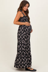 woman wearing a black floral maternity maxi dress and holding her baby bump