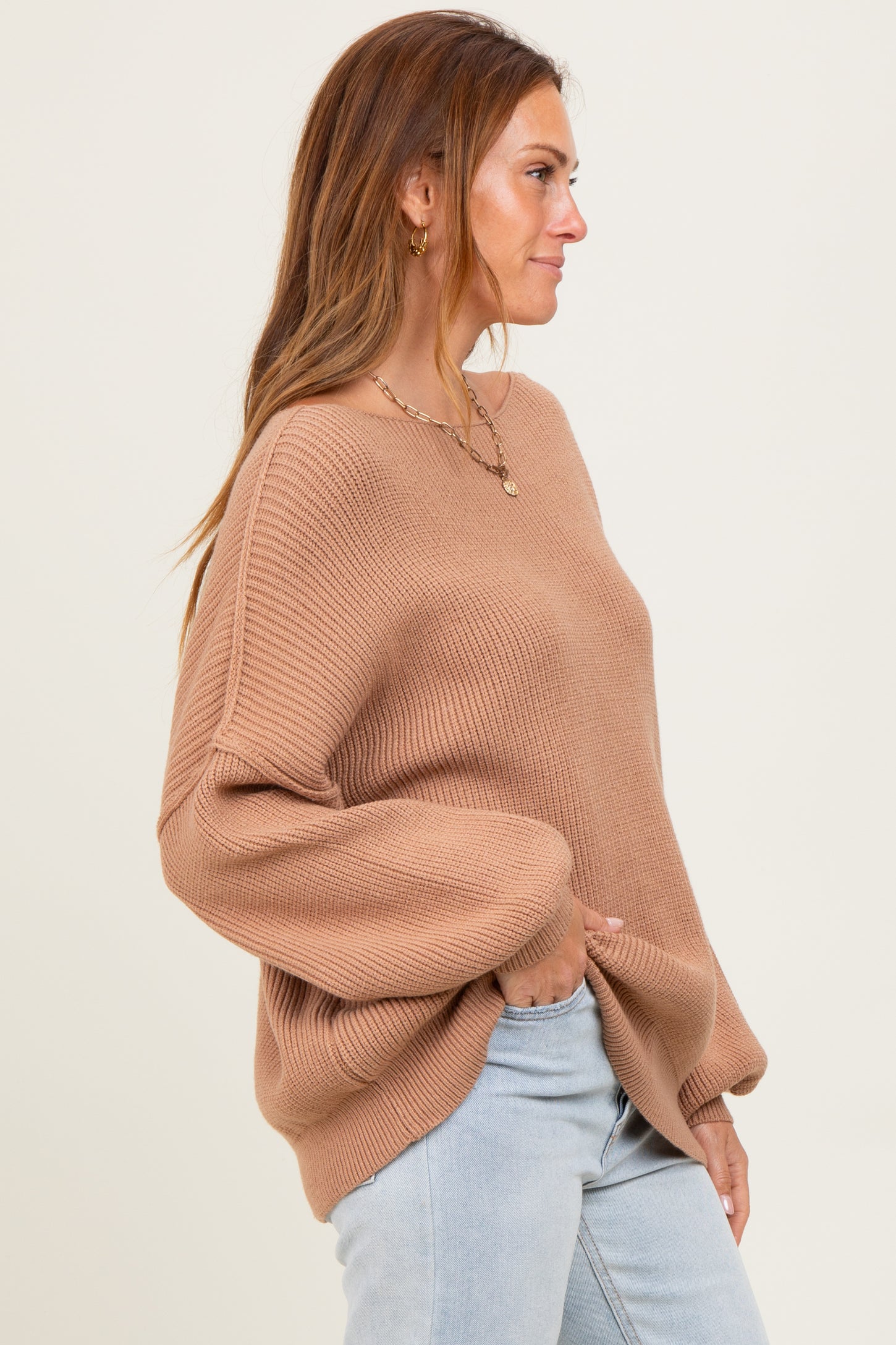 woman wearing a camel oversized ribbed sweater with dropped shoulders and side pockets, paired with light blue jeans