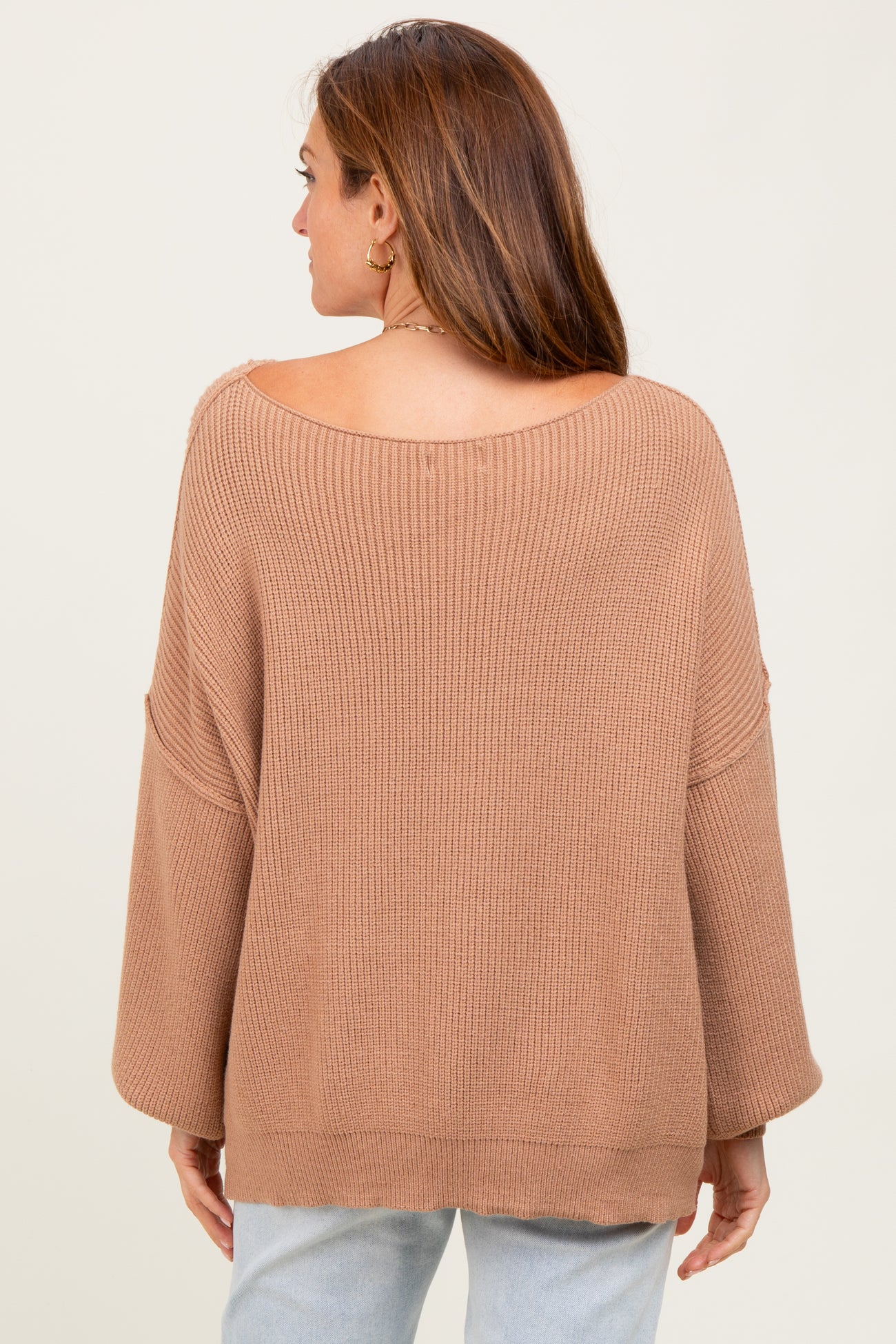 woman wearing a light brown oversized ribbed sweater, showing the back view and soft open neckline