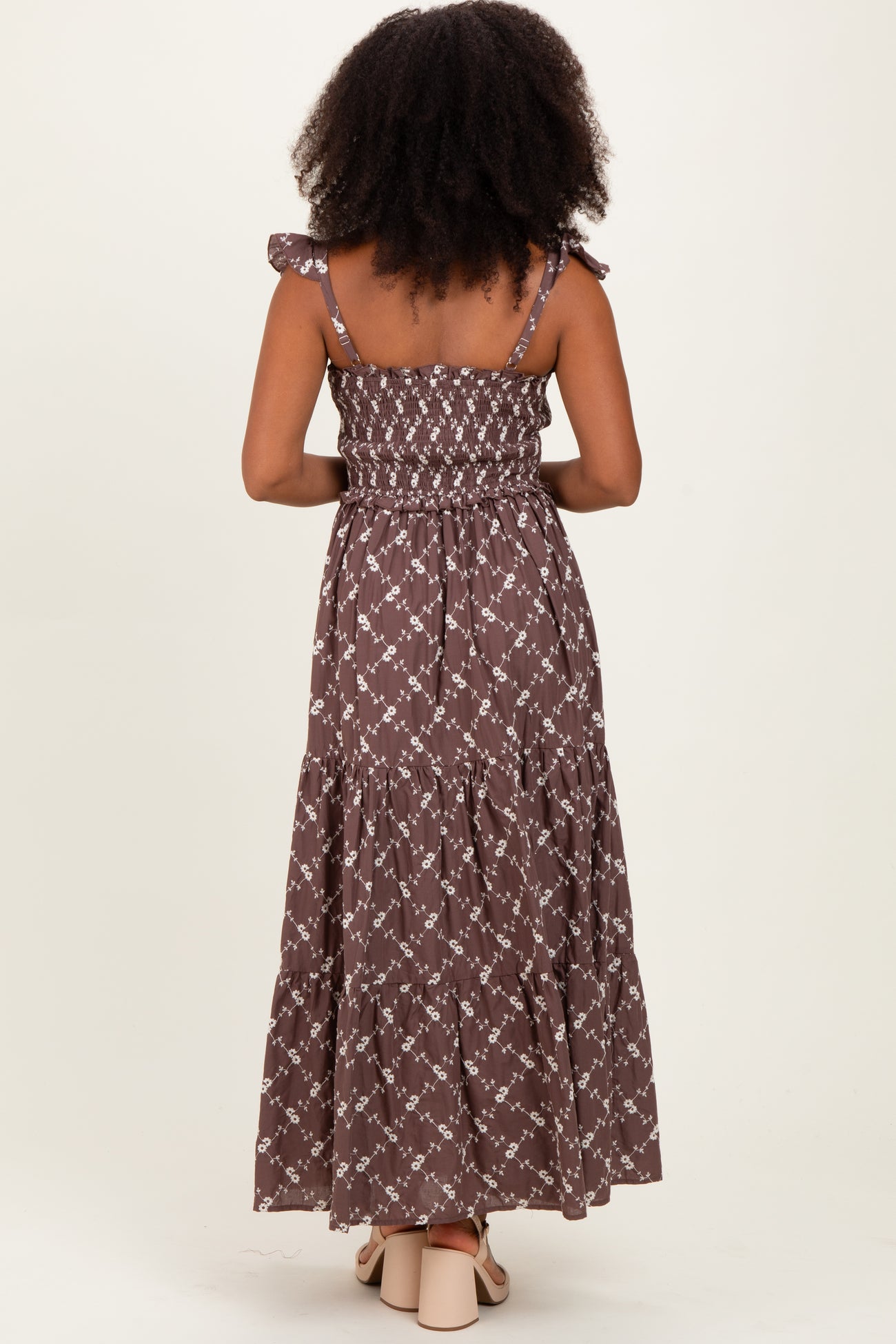 woman wearing a brown floral maxi dress with ruffled straps and a smocked bodice, view from the back