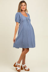 woman wearing a light blue maternity dress with short puff sleeves and a baby bump visible