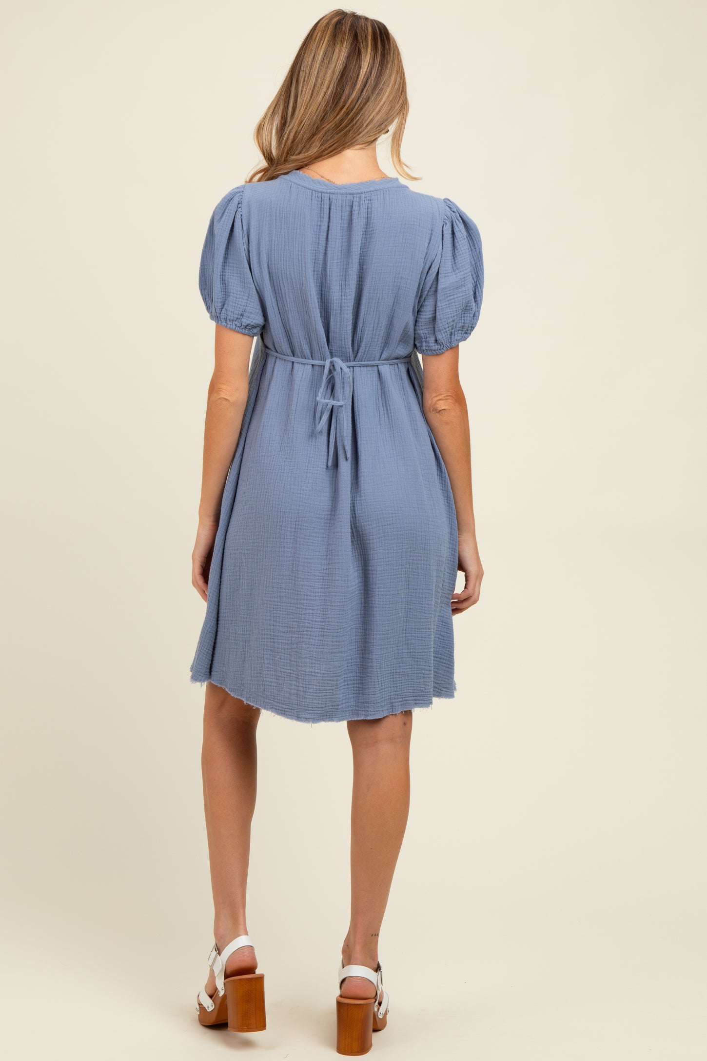 woman wearing a light blue short sleeve maternity dress with a tie-back detail and a relaxed fit