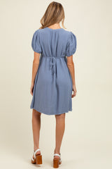 woman wearing a light blue short sleeve maternity dress with a tie-back detail and a relaxed fit