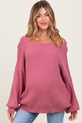 woman wearing a pink oversized maternity sweater with wide sleeves and a loose fit