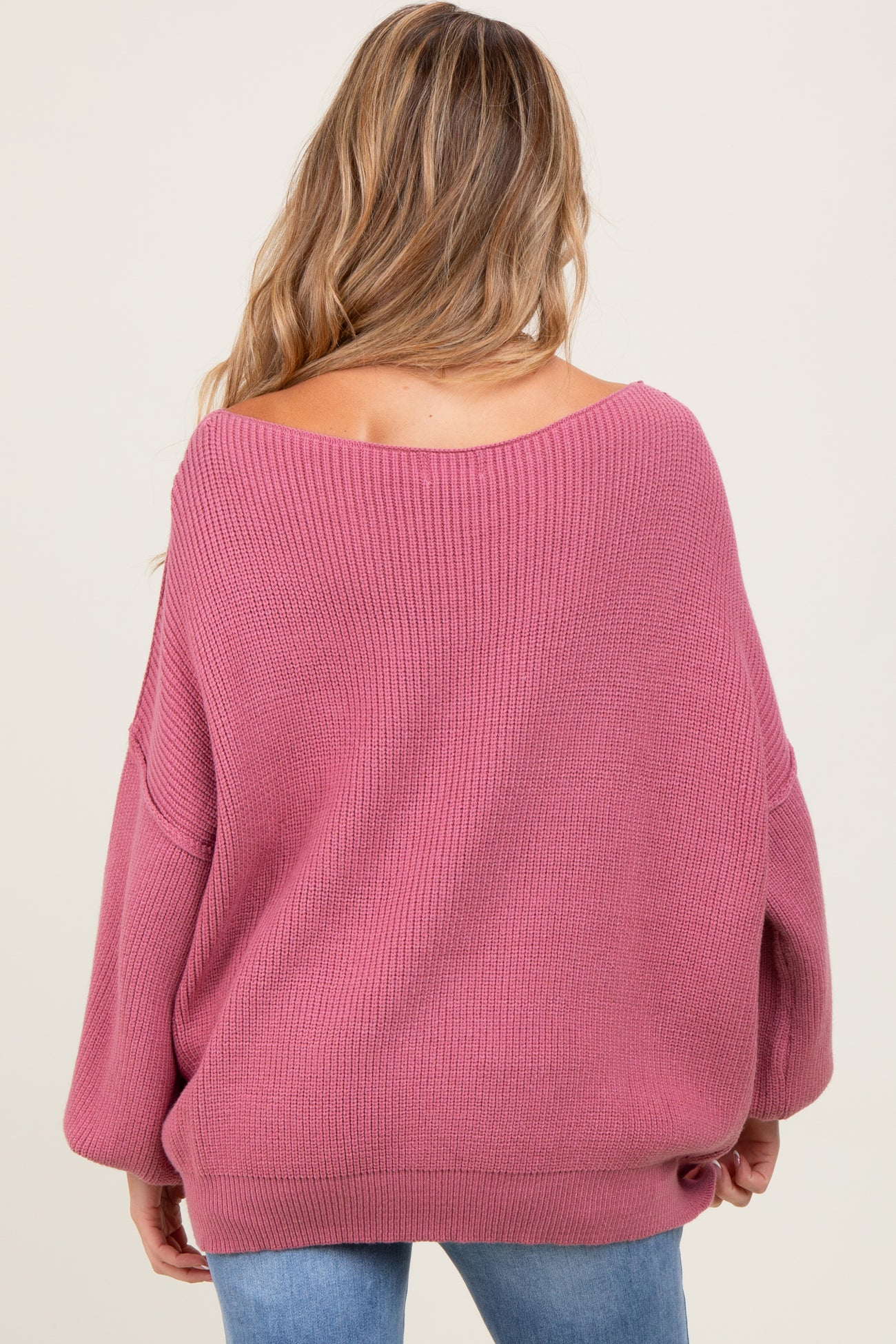 woman wearing a soft pink oversized maternity sweater with a wide neckline and long sleeves