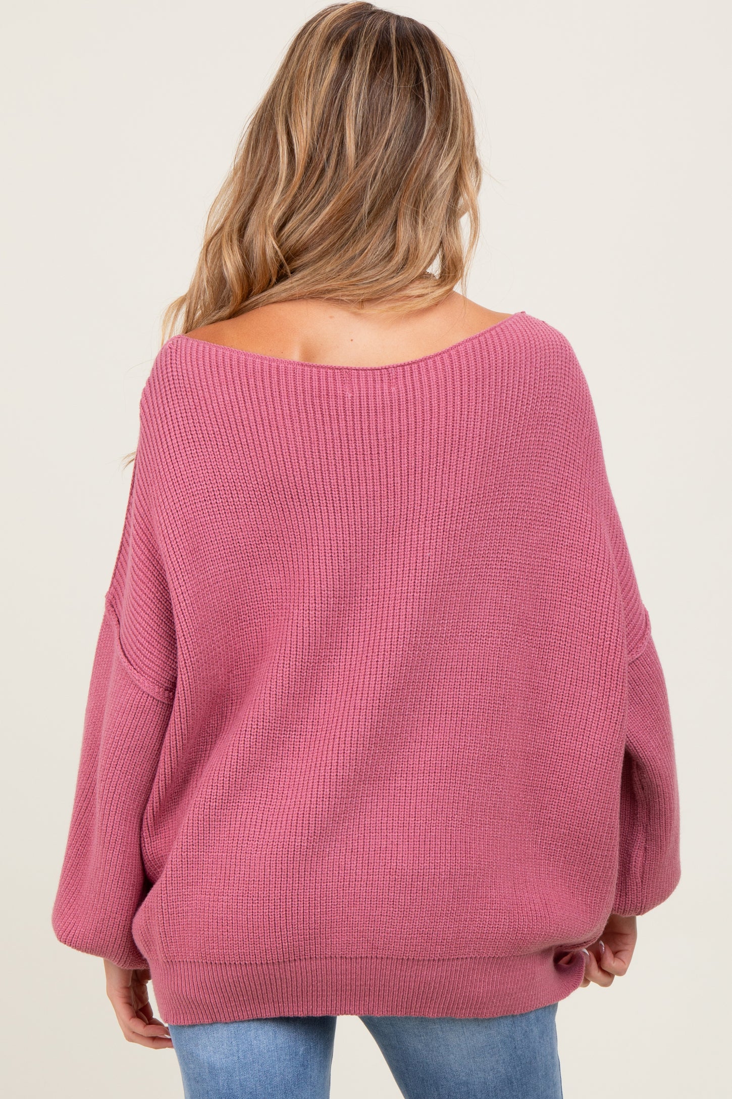 woman wearing a soft pink oversized maternity sweater with a wide neckline and long sleeves