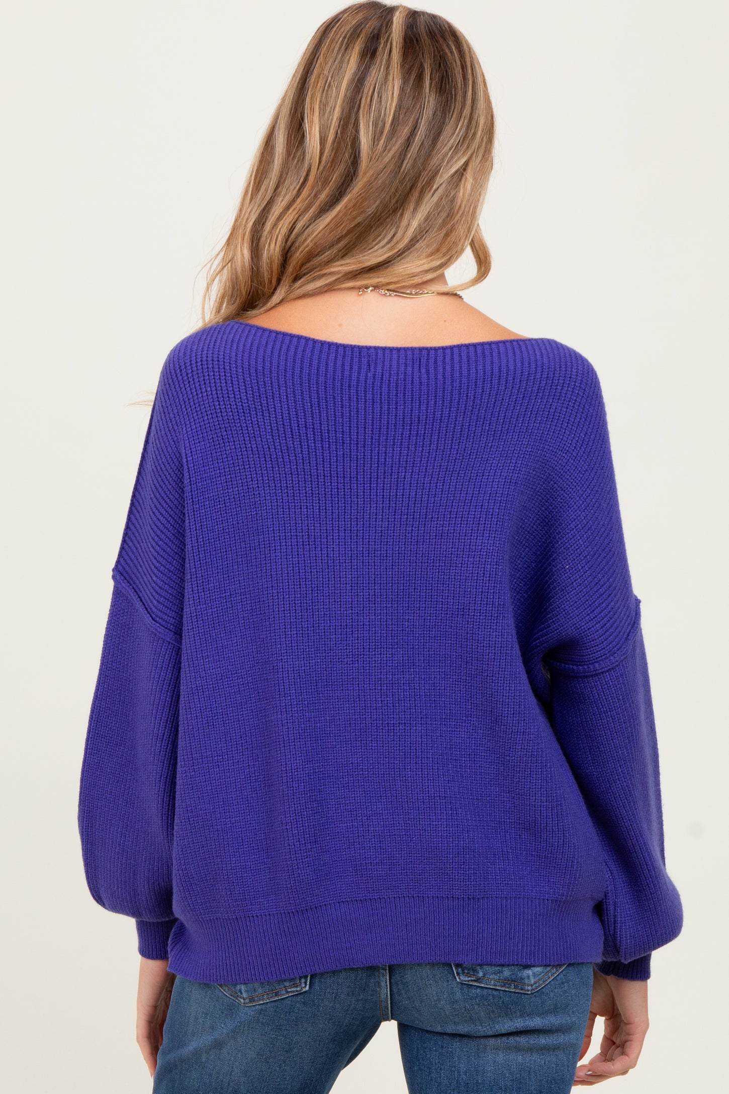 woman wearing a purple oversized maternity sweater with a relaxed fit, seen from the back