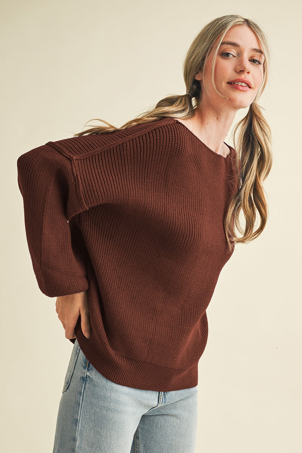 woman wearing a brown oversized ribbed sweater with long sleeves and relaxed fit, smiling at the camera