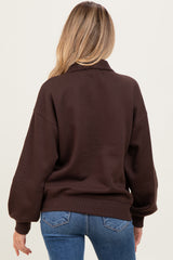 woman wearing a brown oversized maternity sweatshirt, showing the back view with relaxed sleeves and ribbed hem