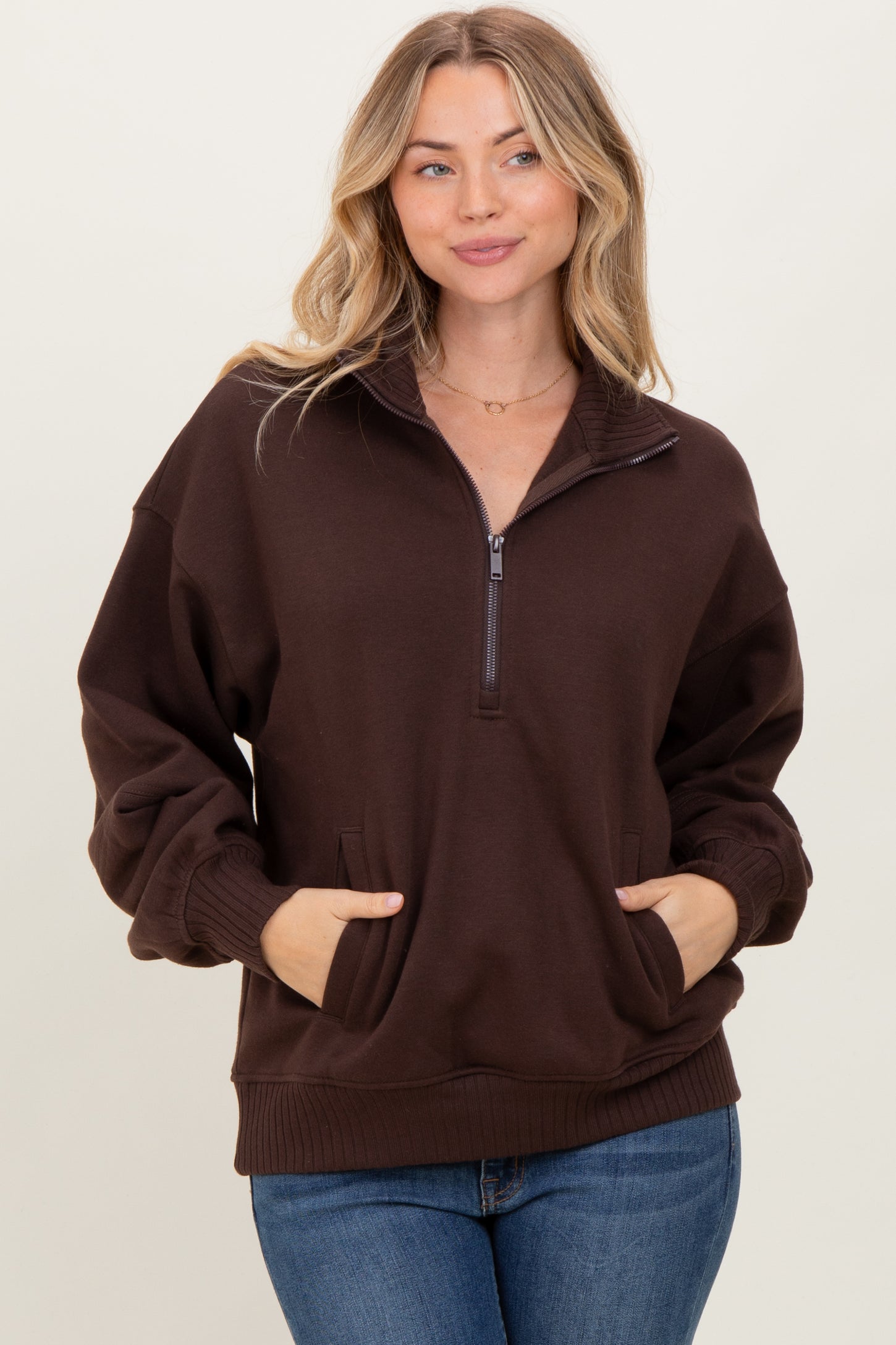 woman wearing a brown half-zip pullover sweatshirt with side pockets and a relaxed fit