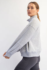 woman wearing a light gray oversized mock neck sweatshirt with ribbed hem and sleeves, paired with black leggings