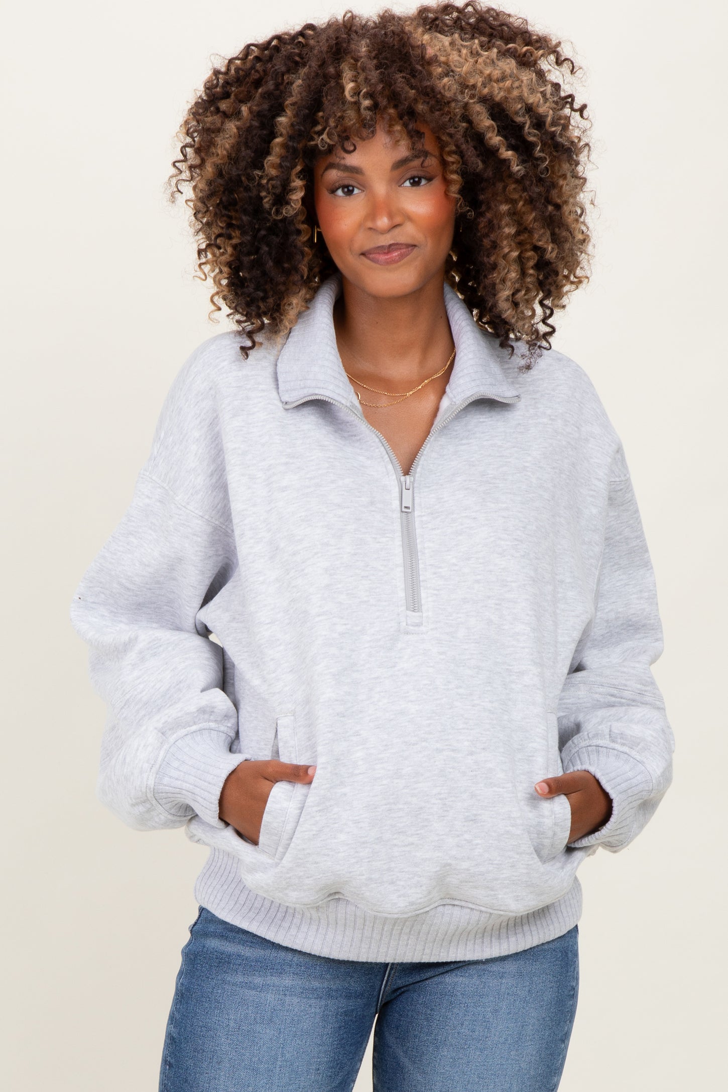 woman wearing a light gray maternity pullover sweatshirt with a half zipper and side pockets