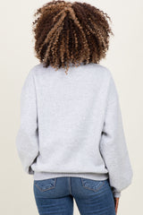 woman wearing a light gray maternity sweatshirt with a relaxed fit, showing the back view and paired with denim jeans