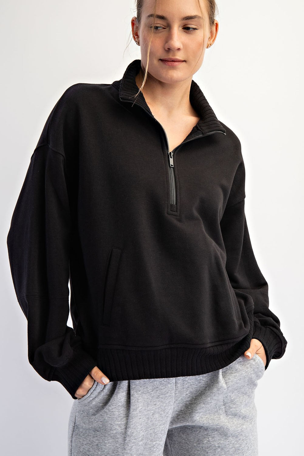 woman wearing a black quarter-zip pullover sweatshirt with a relaxed fit and side pocket, paired with gray sweatpants