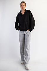 woman wearing a black zip-up sweatshirt and gray wide-leg sweatpants with white sneakers