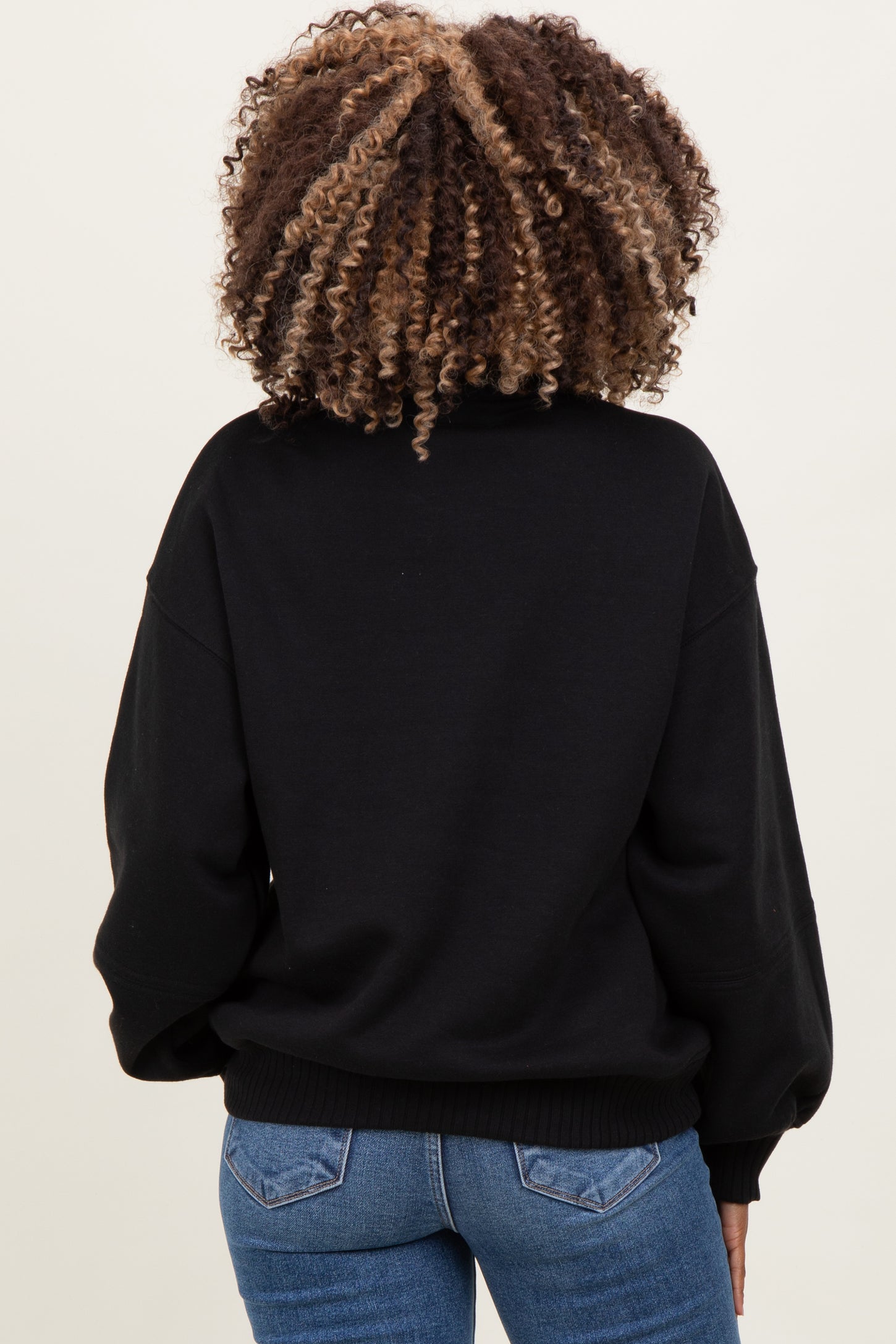woman wearing a black oversized maternity sweatshirt with a relaxed fit and ribbed hem, viewed from the back