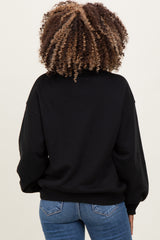 woman wearing a black oversized maternity sweatshirt with a relaxed fit and ribbed hem, viewed from the back