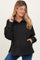 woman wearing a black maternity pullover with a button-up collar and front pockets, smiling and posing