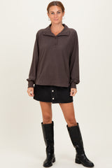 woman wearing a brown pullover sweatshirt with a collar and buttons, paired with a black denim skirt and black knee-high boots