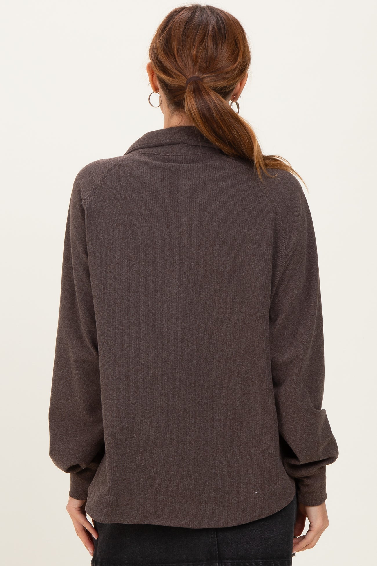 woman wearing a dark brown oversized sweater with a relaxed fit and long sleeves, viewed from the back