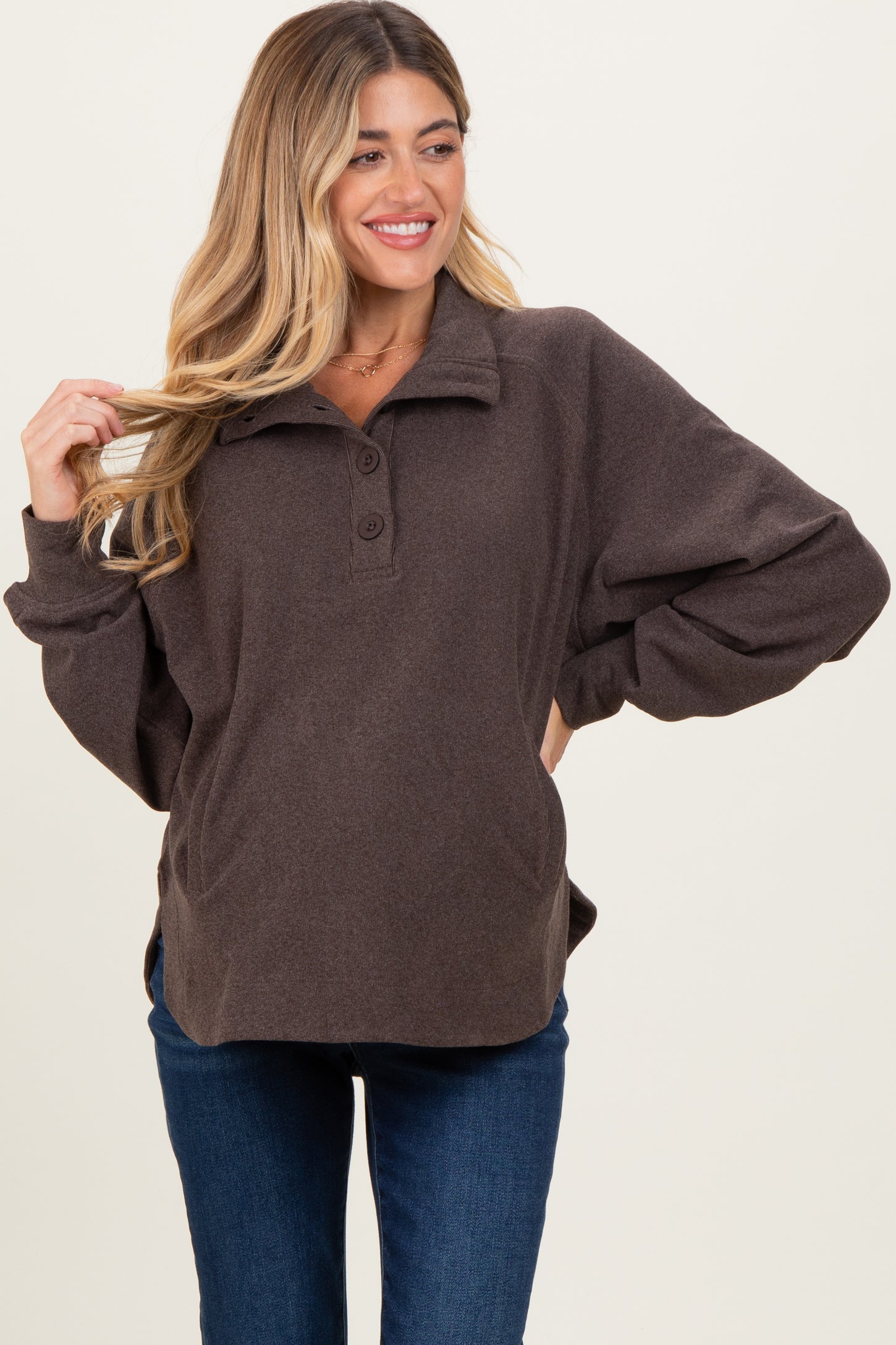 woman wearing a brown fleece maternity pullover with a collar and button details, showing a baby bump