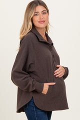 woman wearing a dark brown maternity pullover with a collar and buttons, holding her baby bump