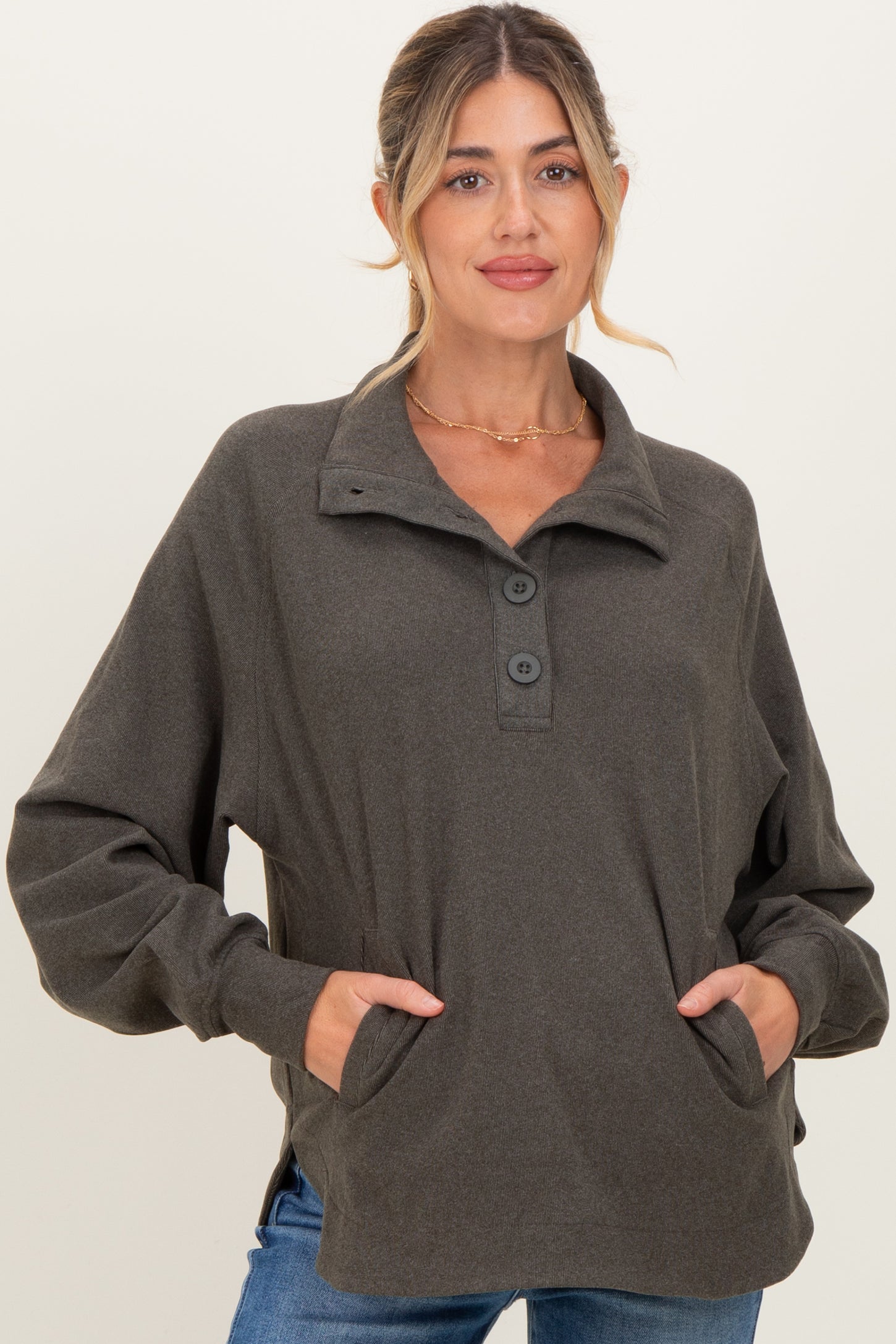 woman wearing a dark green maternity pullover with a button collar and side pockets