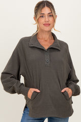 woman wearing a dark green maternity pullover with a button collar and side pockets