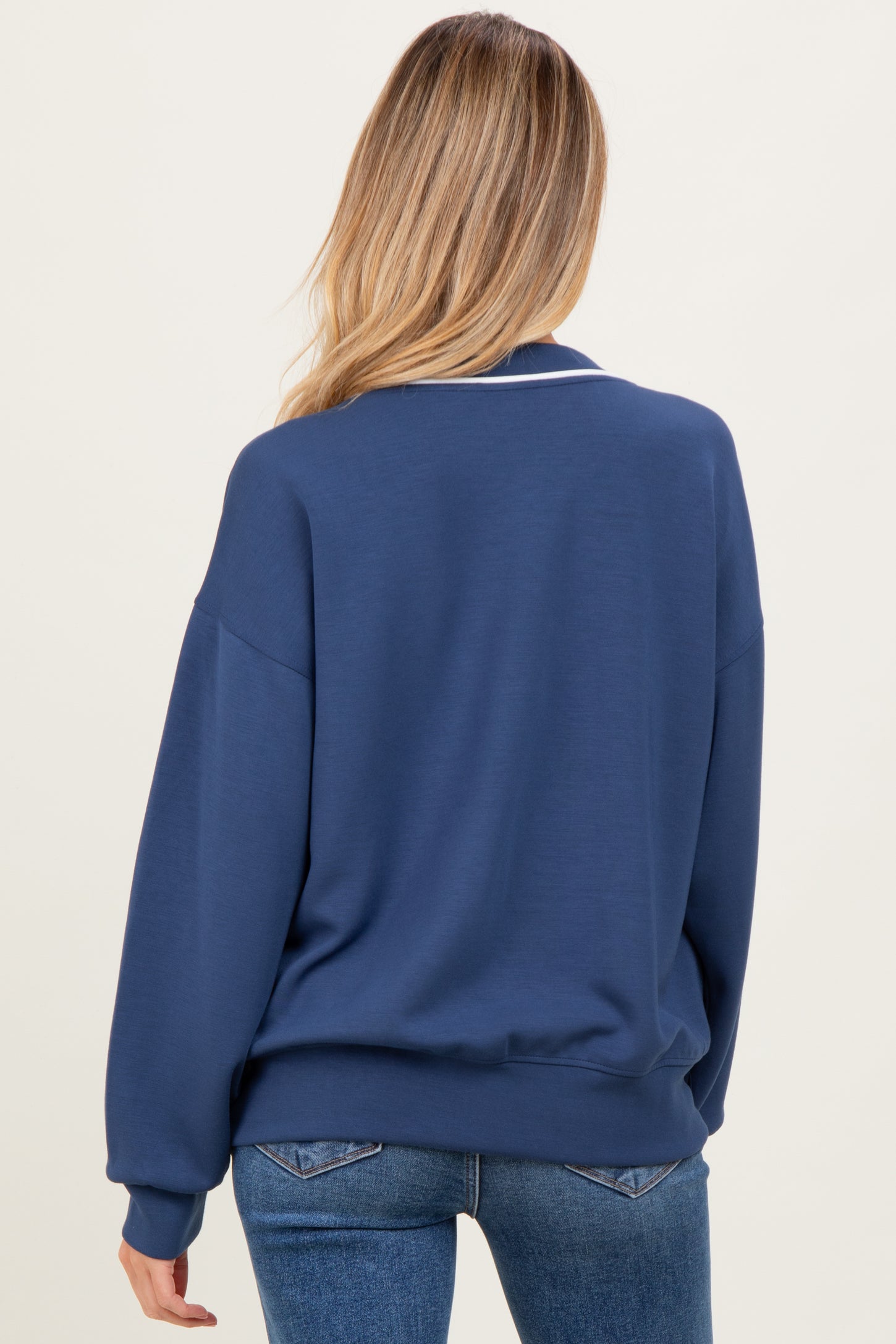 woman wearing a dark blue oversized maternity sweatshirt seen from the back with long sleeves and a relaxed fit