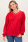 woman wearing a bright red oversized sweatshirt with a v-neckline and white trim, paired with blue jeans