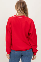 woman wearing a red oversized sweatshirt with white collar detailing, showing the back view