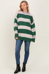 woman wearing a green and cream striped oversized knit sweater with a relaxed fit and blue skinny jeans