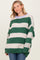 woman wearing a green and cream striped oversized sweater with a round neckline and long sleeves