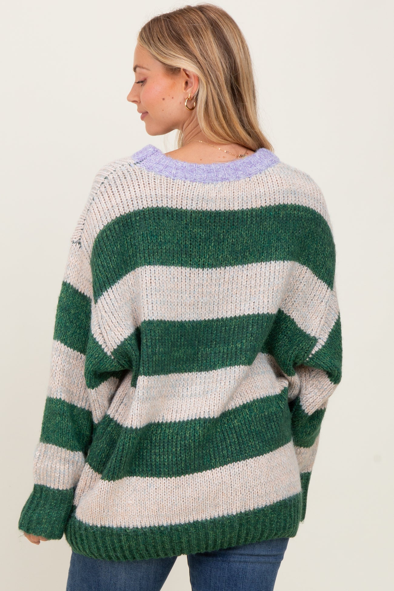 woman wearing a green and beige striped oversized sweater with a purple collar and relaxed fit