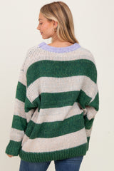 woman wearing a green and beige striped oversized sweater with a purple collar and relaxed fit